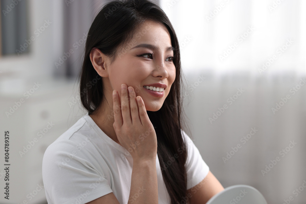 Woman with perfect skin looking at mirror indoors Woman with perfect skin looking at mirror indoors