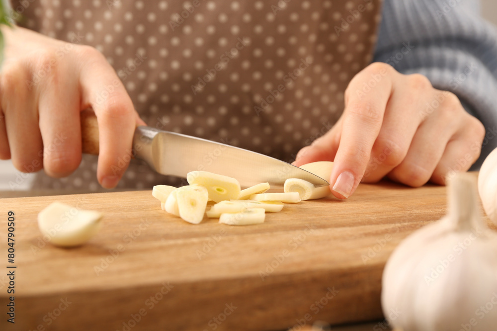 Woman cutting fresh garlic at table, closeup