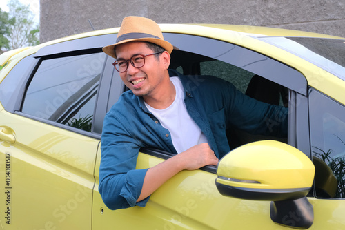 A man smiling and looking away from inside his ccar photo