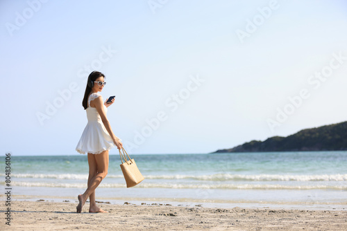 Joyful beautiful woman with white dress walk relax on tropical beach , summer vacation and travel