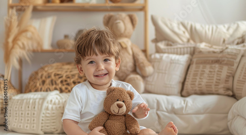 A cute little boy sitting on the floor next to his teddy bear toy, smiling and looking at camera