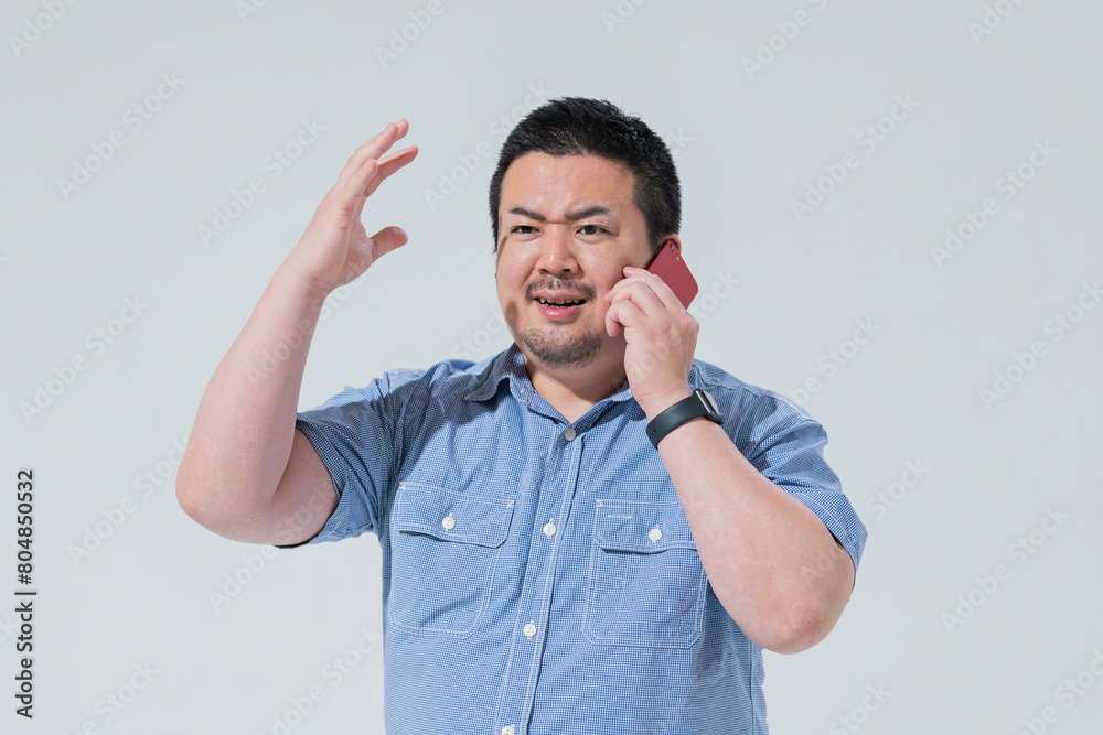 電話をしながら感情的になる大柄な日本人男性 電話をしながら感情的になる大柄な日本人男性