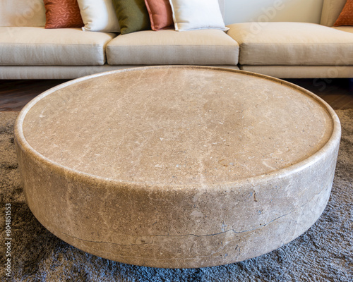 Close-up of marble coffee table with couch in the background in a modern living room. The coffee table has a sleek marble surface and a minimalist frame