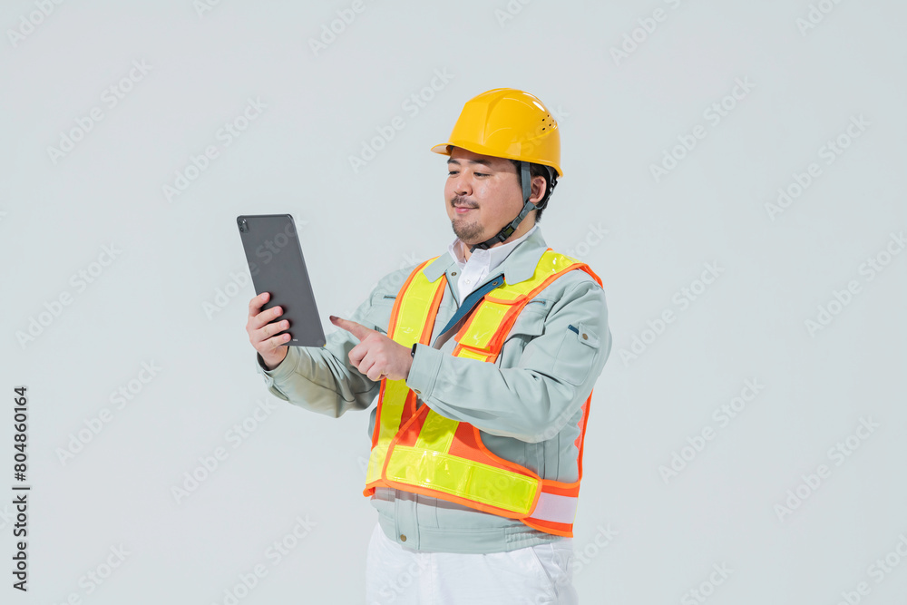タブレット端末を見る作業服の男性 タブレット端末を見る作業服の男性