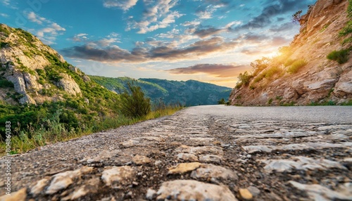 Low level view of empty old paved road in mountain area at sunset; blue cloudy sky; travel concept