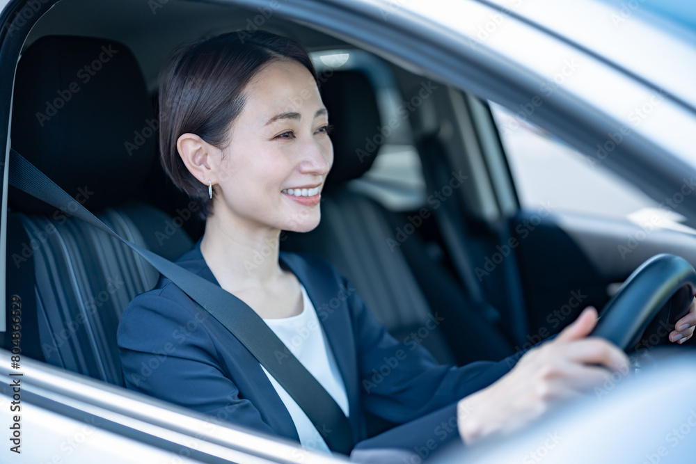 車を運転するスーツを着た女性