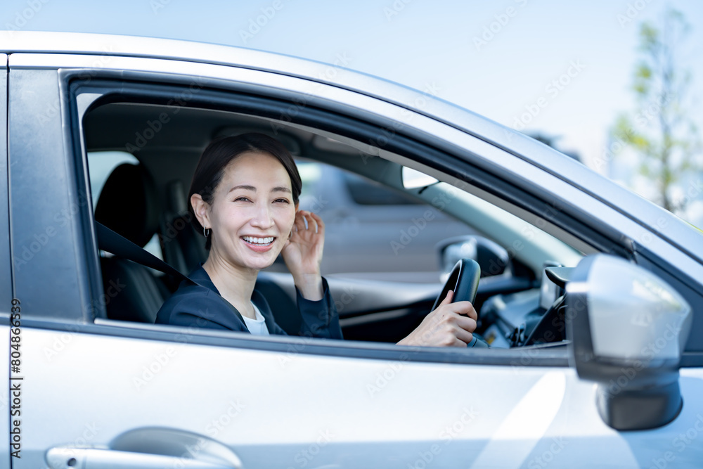 車を運転するスーツを着た女性