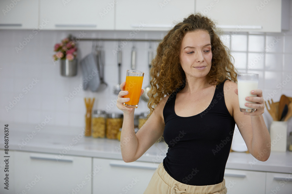 young woman holding orange juice and milk in the kitchen young woman holding orange juice and milk in the kitchen