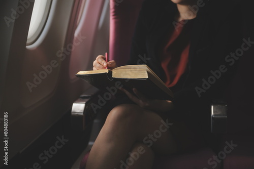 Blonde female tourist checking incoming notification on smartphone sitting on seat of airplane with netbook.Young businesswoman share media from telephone on laptop computer during plane flight