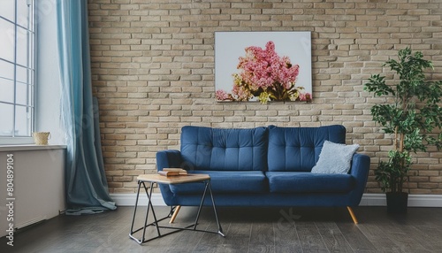 The interior of a modern living room with a dark blue sofa next to a brick wall on which a horizontal poster hangs, in the background you can see a mirror above the cabinet with flowers. 3d