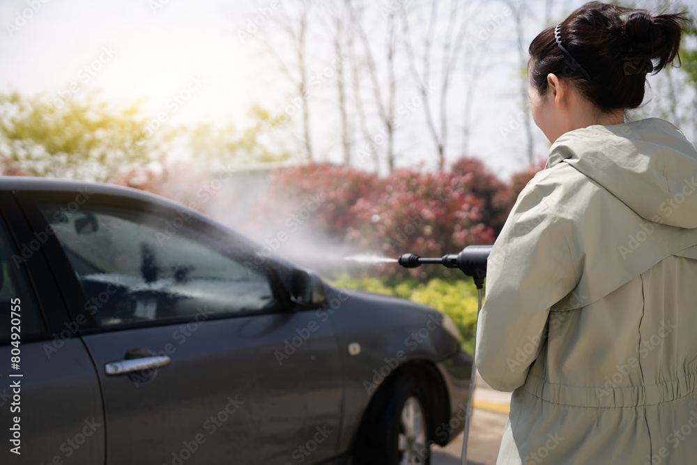 Woman Efficiently Cleans Her Car Outdoors with Washer Woman Efficiently Cleans Her Car Outdoors with Washer