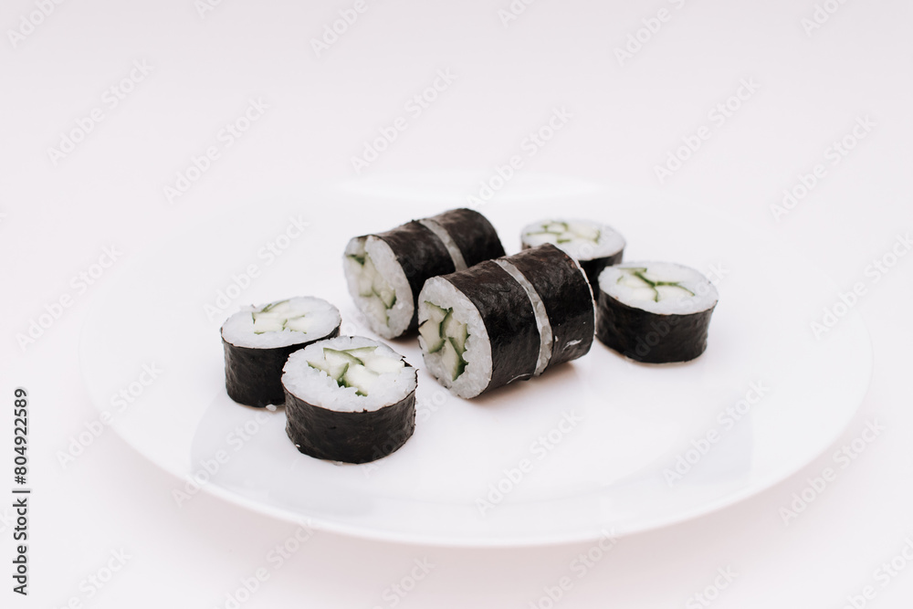 Maki roll with cucumber and avocado on plate Maki roll with cucumber and avocado on plate