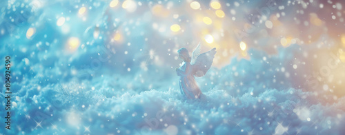 A delicate angel figurine bathed in sparkling lights amidst a snowy, winter setting. © tashechka