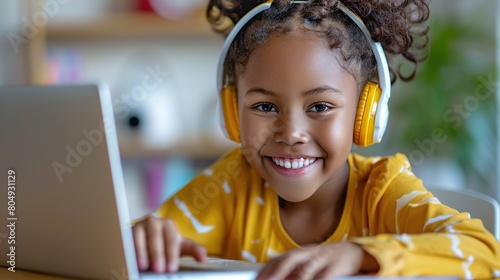 Happy schoolgirl doing homework at home. During pandemic or travel children continue learning process. Mixed-race KId receive assignments from teachers via laptop and headphones. photo