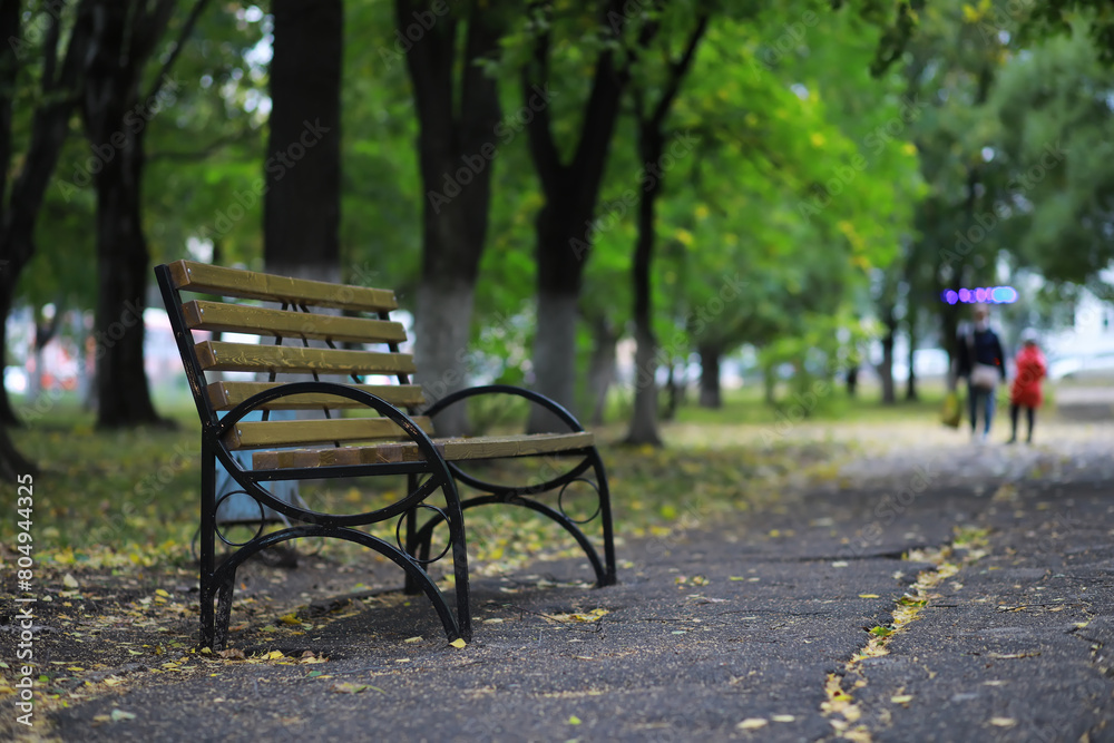 Autumnal park with bench. Falling leaves. Focus on bench