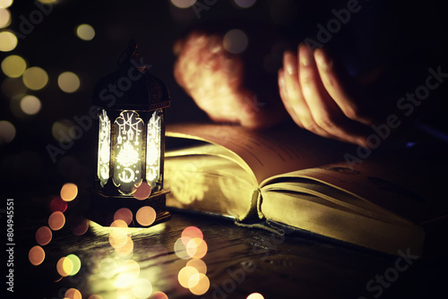 Ramadan Kareem background. Ornamental Arabic lantern glowing and the holy book of Quran. photo