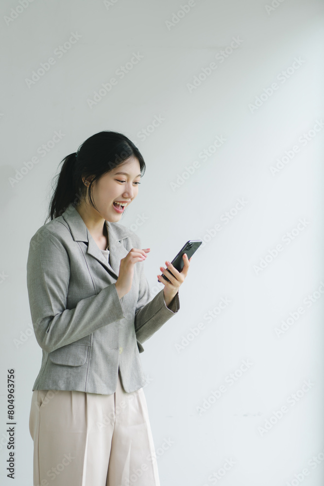Young woman in business attire reacts joyfully to smartphone message in bright office environment. Young woman in business attire reacts joyfully to smartphone message in bright office environment.