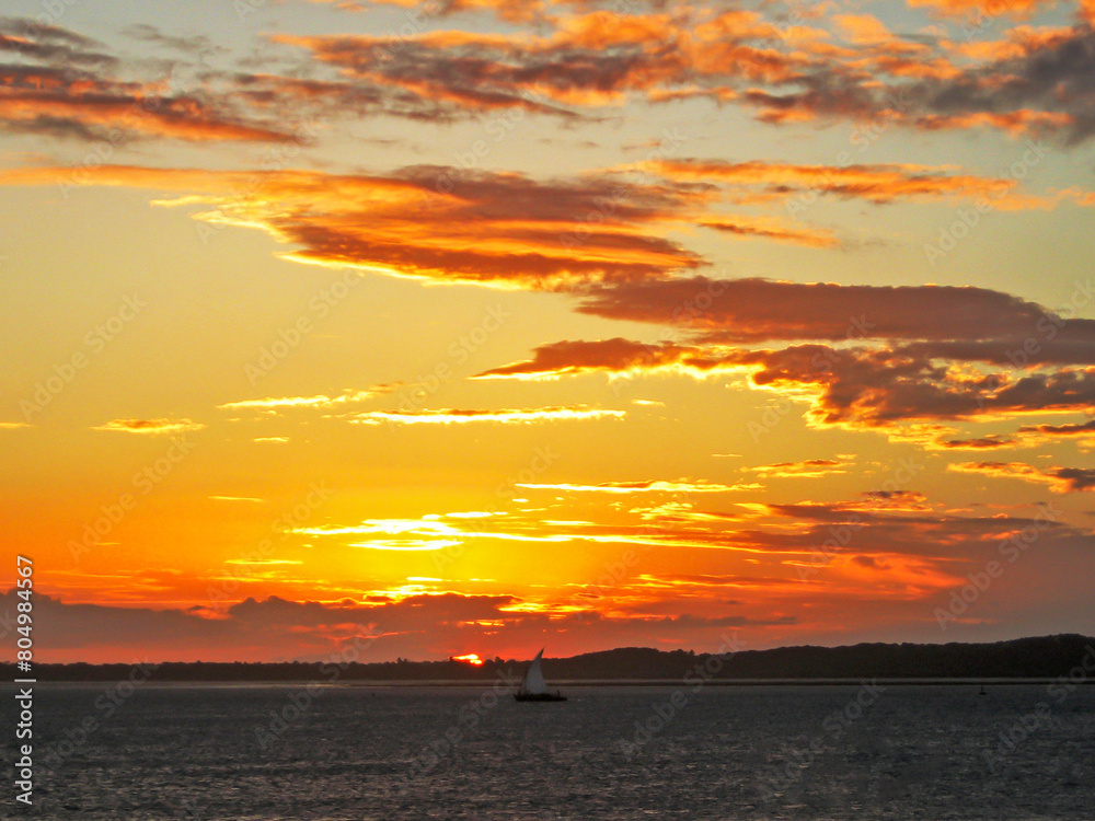 A distant dhow sailing against the golden sunset of the southern coast of Mozambique