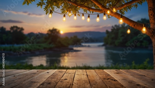 mpty Wood table top with decorative outdoor string lights hanging on tree in the garden , Daylight saving time end, real estate concept and blurred landscape of river beach Blue sky with sunset