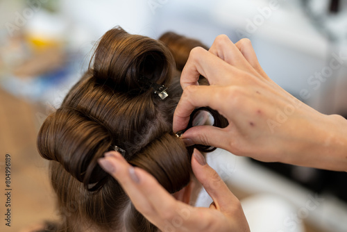 The hairdresser curls the model's hair. Curling iron for curling hair close-up.