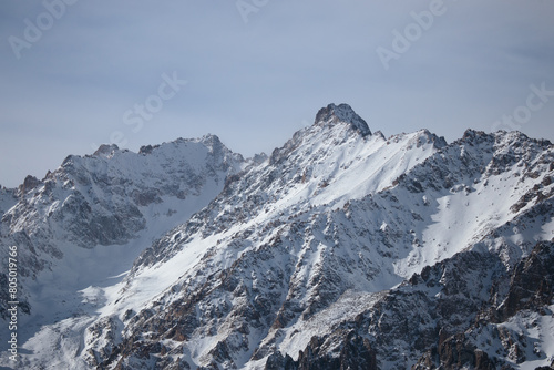 Winter landscape with snowy mountains and clouds. High mountain peaks covered with a layer of snow. Amazing nature scenery with highland rocks