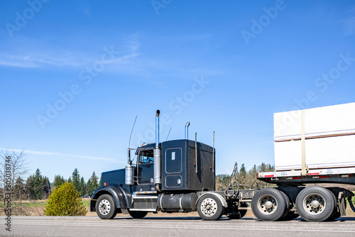 Εκτύπωση καμβά Extended cab black classic big rig semi truck transporting cargo on flat bed sem