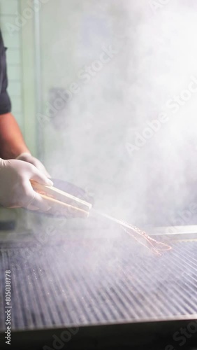 Chef placing octopus on a hot grill in the restaurant kitchen.