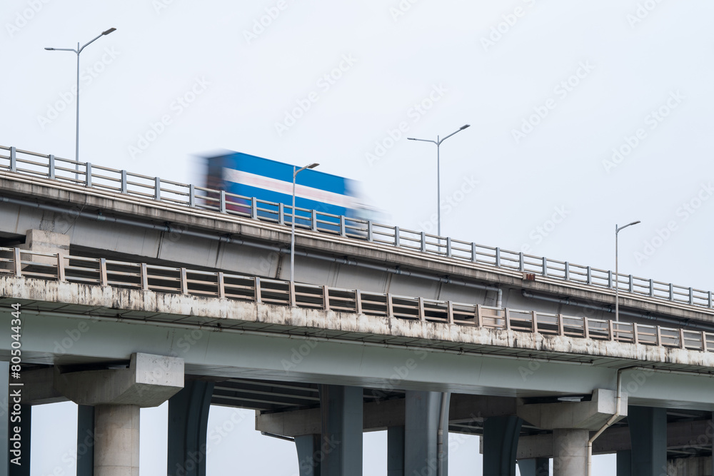 Modern highway bridge and a motion blurred blue truck driving fast on the bridge.