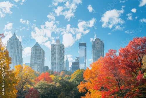 A wide-angle view of a city skyline showcasing tall buildings in the background and fall foliage trees in the vicinity