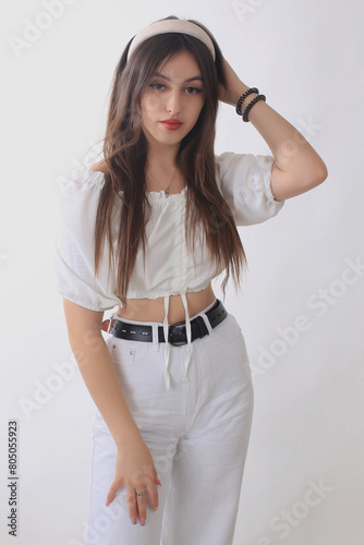 Portrait of a beautiful fashion model in the studio on a light background, wearing a hoop and white trousers photo