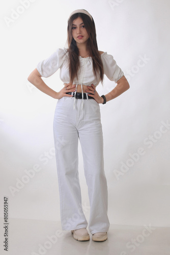 Portrait of a beautiful fashion model in the studio on a light background, wearing a hoop and white trousers photo