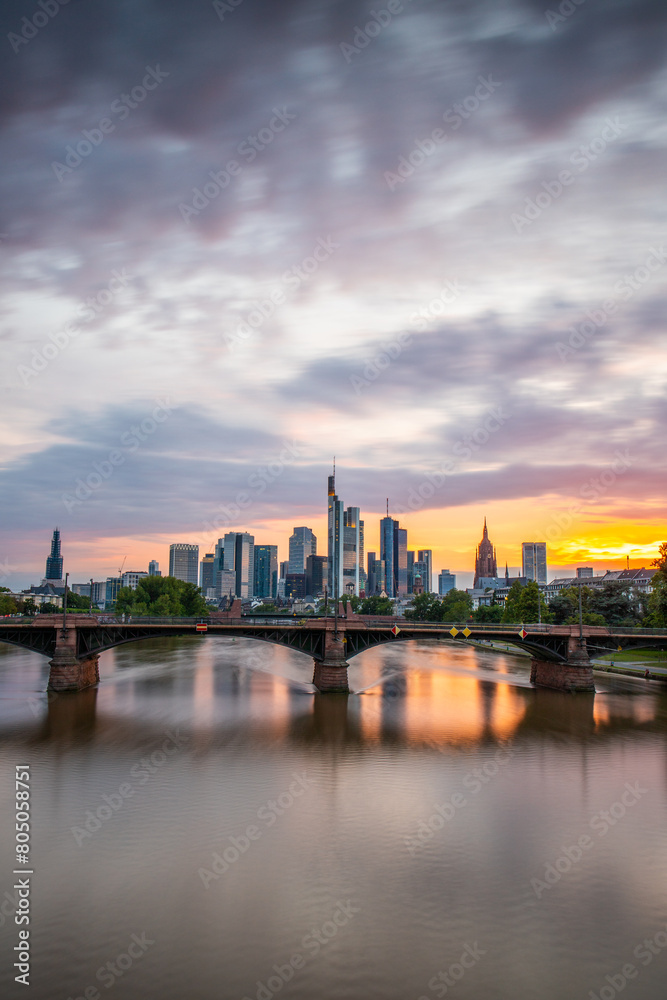 View from a bridge over the River Main to a skyline in the financial district in the background as the sun sets. Twilight in Frankfurt am Main, Hesse Germany