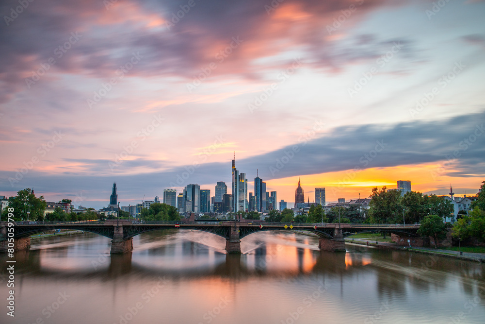 View from a bridge over the River Main to a skyline in the financial district in the background as the sun sets. Twilight in Frankfurt am Main, Hesse Germany
