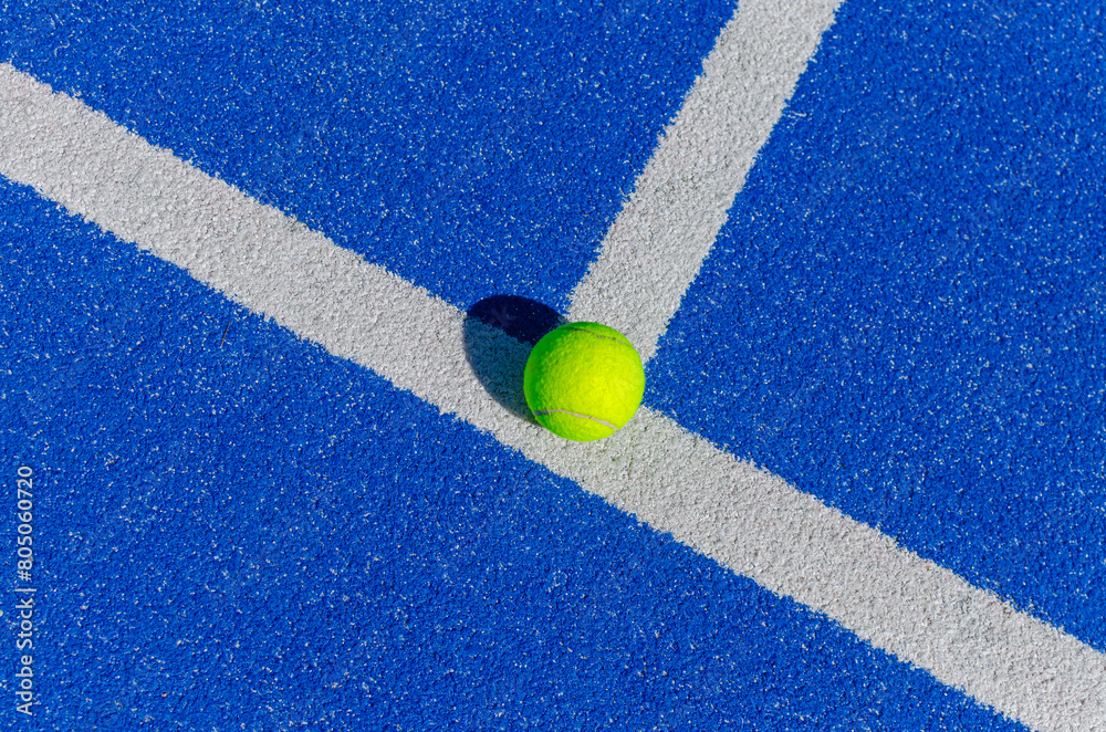 ball on the lines of a blue paddle tennis court, racket sports concept