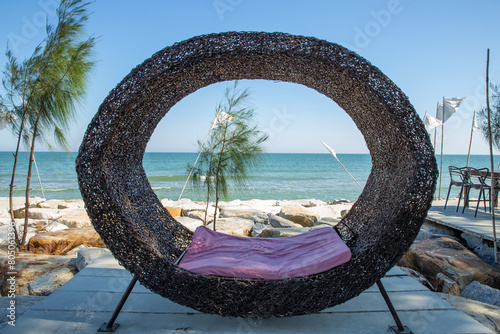 The wooden seat is shaped like a bird's nest with a beautiful sea view.