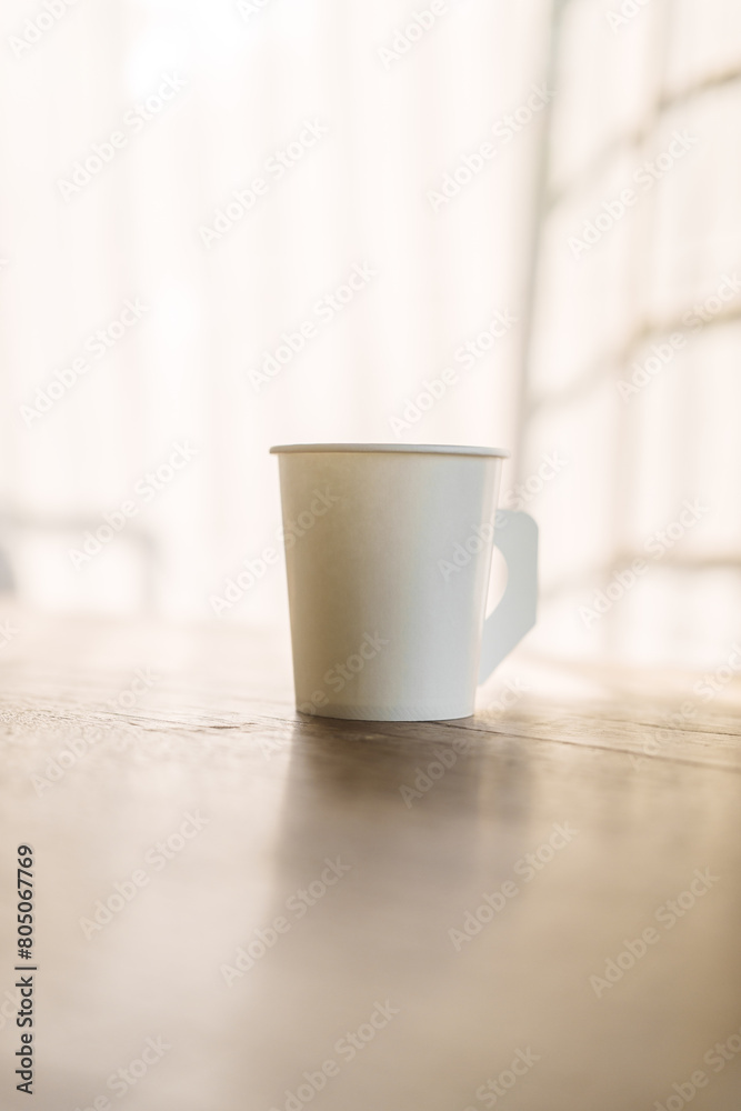 A paper coffee cup placed on a desk indoors, depicting a brief moment of pause or productivity. Workplace essentials, coffee break, and office culture converge. A paper coffee cup placed on a desk indoors, depicting a brief moment of pause or productivity. Workplace essentials, coffee break, and office culture converge.