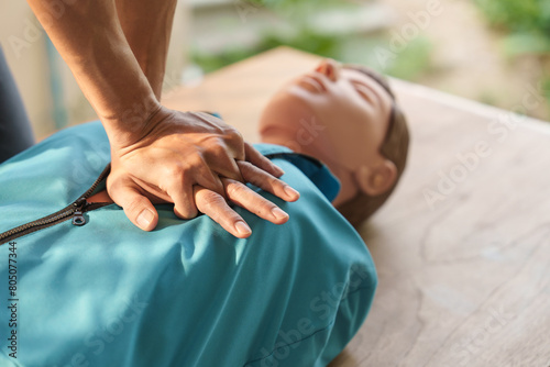 Fotografie Close-up of middle-aged Asian male hands performing cardiopulmonary resuscitation (CPR) on a training dummy