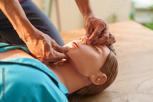 Fotografi Close-up of middle-aged Asian male hands performing cardiopulmonary resuscitation (CPR) on a training dummy