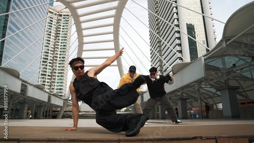 Group of professional street dancer cheer up while asian hipster perform freestyle footstep at city surrounded by people with low angle camera. Break dance concept. Outdoor sport 2024. Sprightly.
