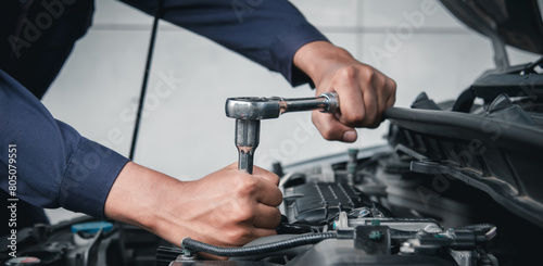 Mechanic using wrench while working on car engine outside the service center , Repair and service. © Nonthanat
