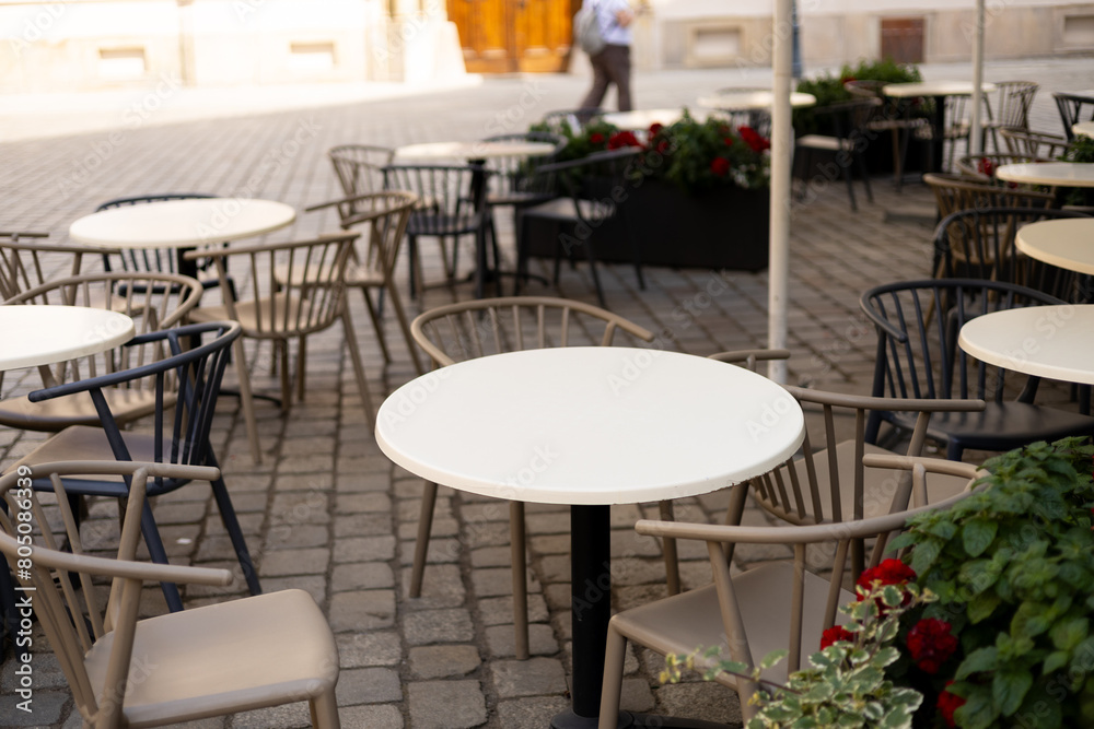 Outdoor street cafe tables ready for service. Modern Empty cafe terrace with table and chair, morning time. Food concept. Cafeteria, Outside Trattoria