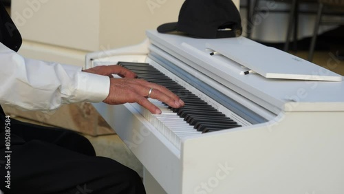 Old pianist creates magic with glissando on white piano. photo