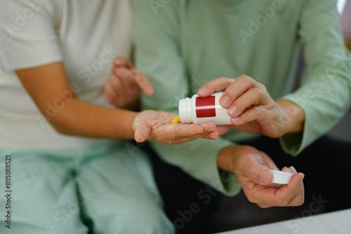 Elderly woman pouring capsules from pill bottle. Healthcare concept © Prathankarnpap