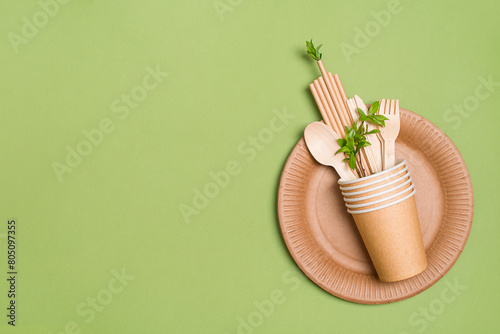 Eco concept. Zero waste disposable kraft paper food containers set over green background with leaves and copy space.