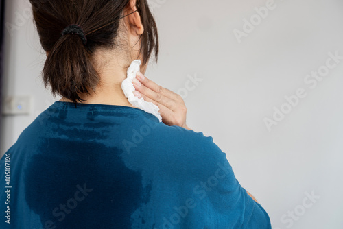 back view of sweating woman with wet cloth because of hot weather in summer time, menopause symptom concept