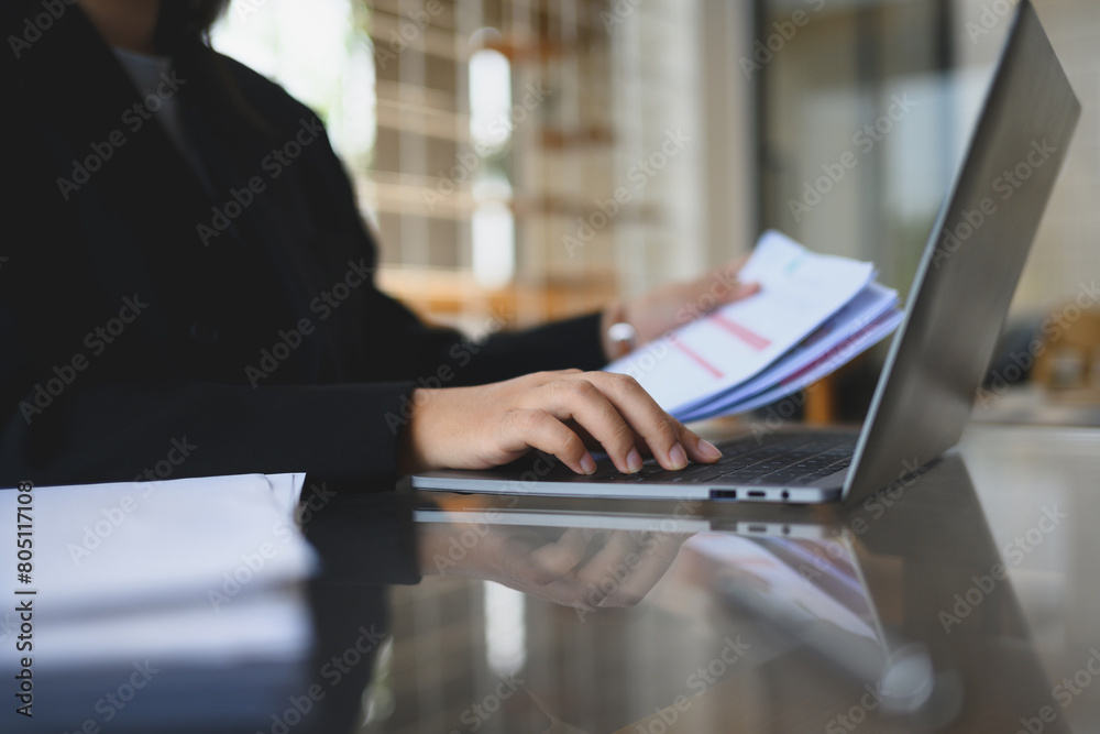 Young businessman in black suit checking financial reports at modern workplace