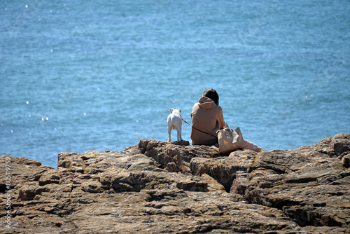 Frau mit Hund schaut aufs Meer