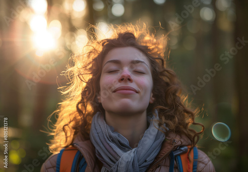 A beautiful woman with her eyes closed, dressed in hiking gear, enjoys the tranquility of nature.