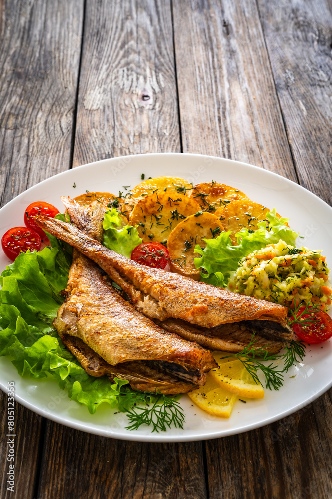Fried sea bass with fried potatoes and fresh cabbage salad on wooden table
Fried sea bass with fried potatoes and fresh cabbage salad on wooden table