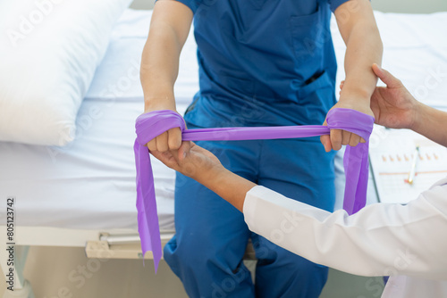 doctor is examining muscle injury and using elastic bands test injury and also help with physical therapy strengthen muscles because physical therapy will help strengthen muscles and help blood flow.